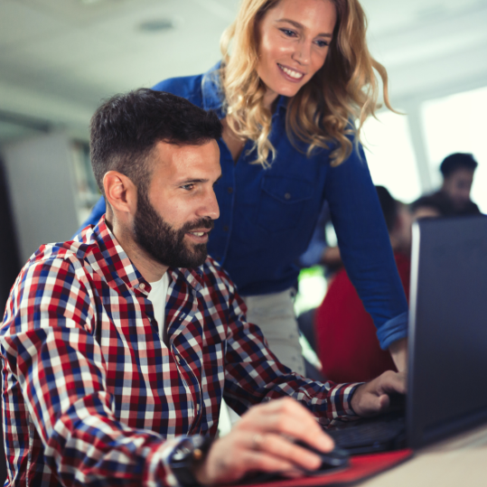Two colleagues reviewing automated workflows together on a laptop in a modern office